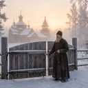 Старець біля воріт сибірського монастиря на світанку.